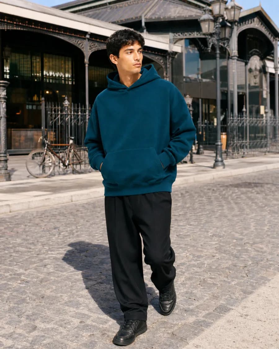 El mismo modelo con la hoodie azul petróleo caminando por el empedrado de San Telmo
